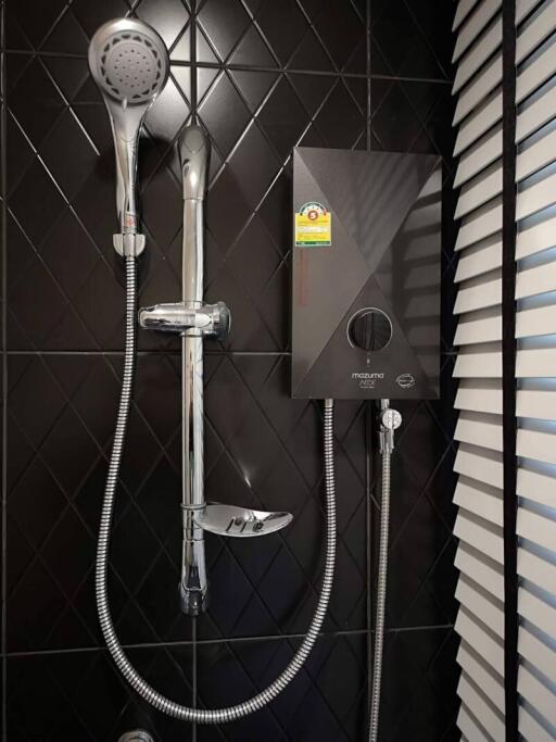 modern bathroom shower with black tiled wall and water heater