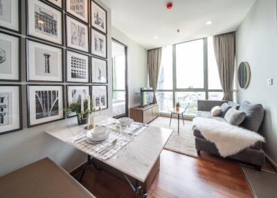 Living area with large windows, a sofa, a small dining table, and wall artwork