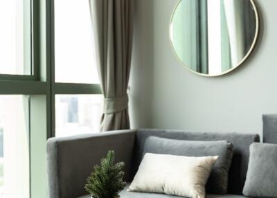 Modern living room with a gray sofa, wooden coffee table, and large windows