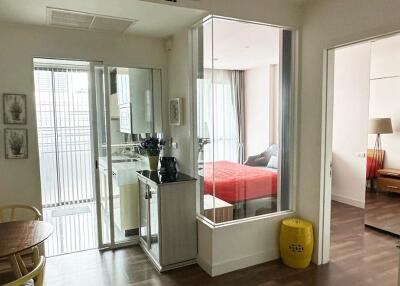 View of an apartment interior showing a small dining area, glass-enclosed kitchen, and two bedrooms