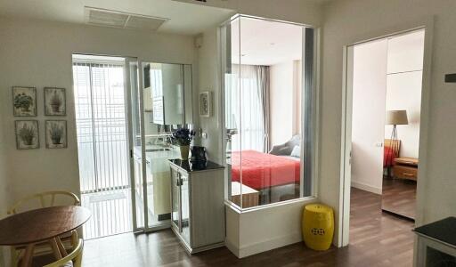 View of an apartment interior showing a small dining area, glass-enclosed kitchen, and two bedrooms