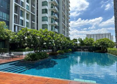 View of a modern apartment building with a swimming pool and surrounding greenery