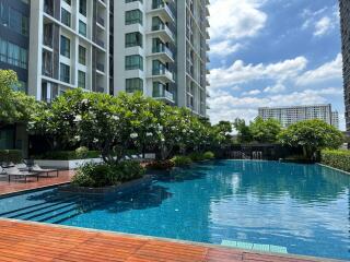 View of a modern apartment building with a swimming pool and surrounding greenery