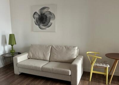 Living room with beige sofa, green lamp, yellow chair, and wall art