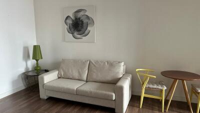 Living room with beige sofa, green lamp, yellow chair, and wall art