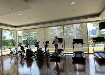 Well-equipped fitness center with several cardio machines and a person exercising