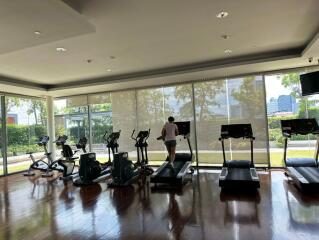 Well-equipped fitness center with several cardio machines and a person exercising