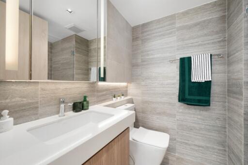 Modern bathroom with sink, toilet, and towels