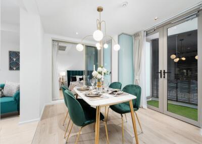 Modern dining room with green chairs, decorative lighting, and a table set for four people.