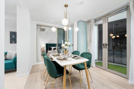 Modern dining room with green chairs, decorative lighting, and a table set for four people.