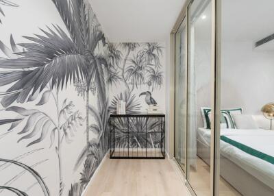 Stylish bedroom with tropical-themed wallpaper and glass sliding door