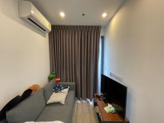 Small living room with sofa, air conditioner, TV, and window curtains