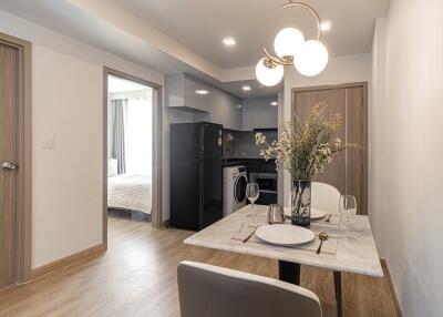 Modern dining area with view into the kitchen and a bedroom