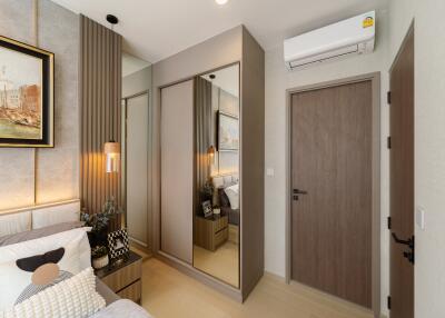 A well-decorated bedroom with modern furnishings, a mirrored wardrobe, and air conditioning.