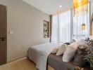 Cozy bedroom with a neatly made bed, built-in shelves, and large windows with sheer curtains