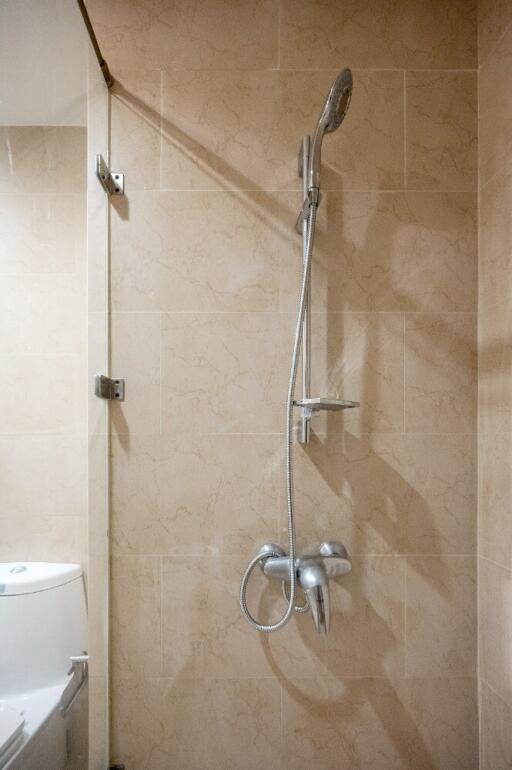 Shower area in a bathroom with beige tiles