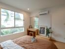 Bedroom with bed, large window, mirror, desk, and air conditioner