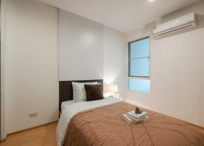 Modern bedroom with a single bed, bedside lamp, and air conditioning unit