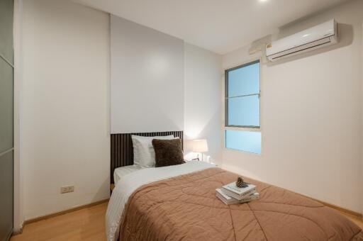 Modern bedroom with a single bed, bedside lamp, and air conditioning unit