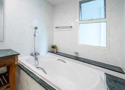 Bathroom with a bathtub, showerhead, and window