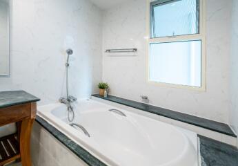 Bathroom with a bathtub, showerhead, and window