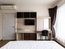 Modern bedroom with a wall-mounted TV, air conditioning unit, and desk