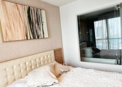 Well-lit modern bedroom with large framed wall art and a window offering a view.