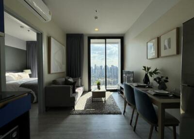 Modern living area with a view of the bedroom, dining area, and cityscape through large windows