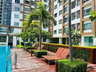 Outdoor pool area with lounging chairs and landscaped garden at an apartment complex