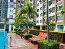 Outdoor pool area with lounging chairs and landscaped garden at an apartment complex