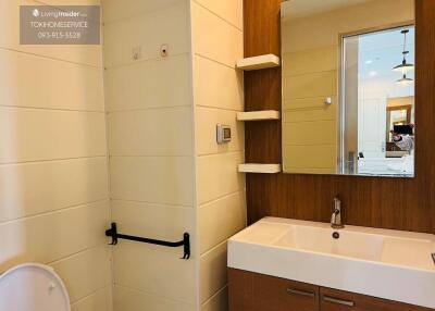 Modern bathroom with sink, mirror, shelves, and toilet