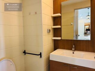 Modern bathroom with sink, mirror, shelves, and toilet