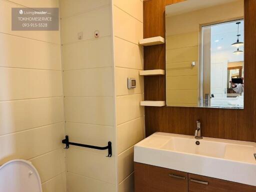 Modern bathroom with sink, mirror, shelves, and toilet