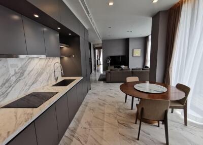 Modern kitchen and open living area with marble countertops and dining table