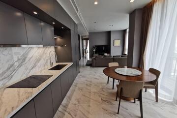 Modern kitchen and open living area with marble countertops and dining table