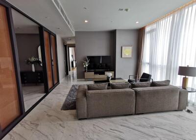 Modern living room with grey sofa, TV unit, and large windows