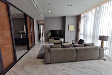 Modern living room with grey sofa, TV unit, and large windows