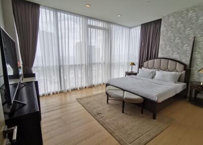 Well-lit bedroom with large windows, beige walls, and modern furniture