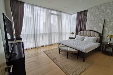 Well-lit bedroom with large windows, beige walls, and modern furniture