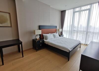 Bedroom with bed, side tables, lamps, desk, and large window with sheer curtains