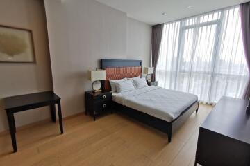 Bedroom with bed, side tables, lamps, desk, and large window with sheer curtains