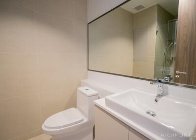 Modern bathroom with sink, toilet, and large mirror