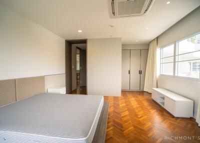 Modern bedroom with large window, wood flooring, and built-in closet