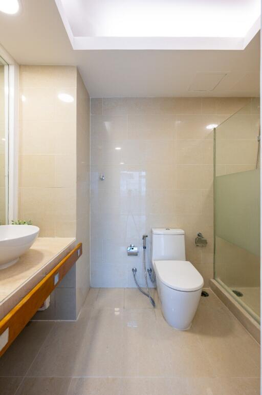 A well-lit bathroom with a modern sink, toilet, and shower