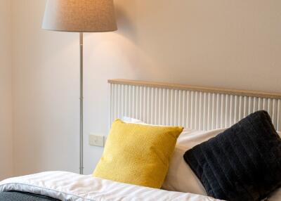 Cozy bedroom with colorful cushions and a standing lamp