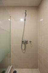 Shower area with beige tiles