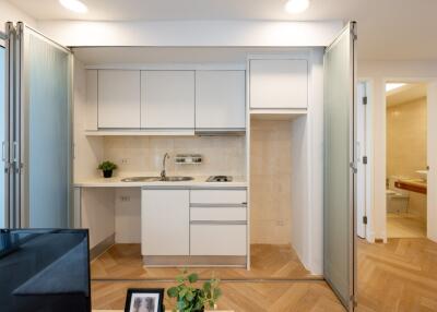 Modern compact kitchen with white cabinets and built-in stove