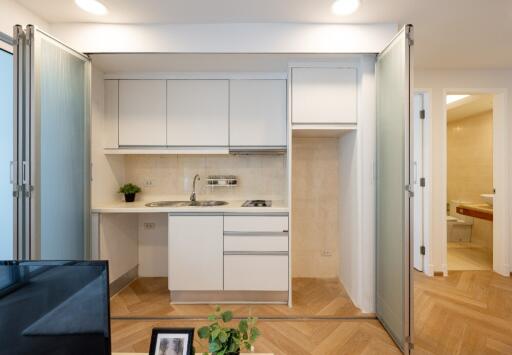 Modern compact kitchen with white cabinets and built-in stove