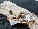 Bed with a neatly arranged tray containing a book, a candle, a flower, and a newspaper