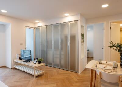 Modern living room with parquet flooring, TV, and dining area